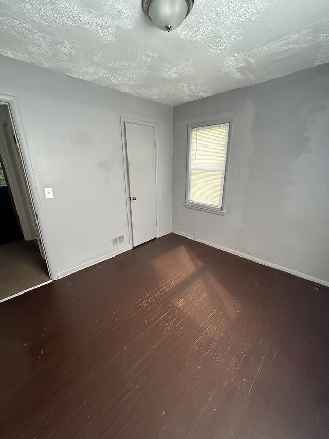 928 Mann Ave, Flint, MI 48503 - empty room with dark wood-type flooring, a textured ceiling, and baseboards