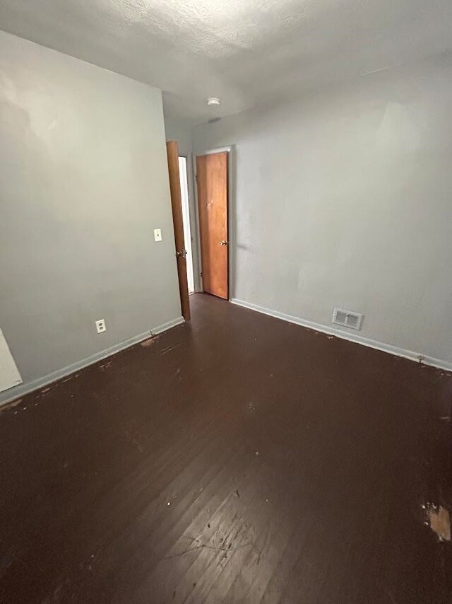 spare room with dark hardwood / wood-style flooring and a textured ceiling