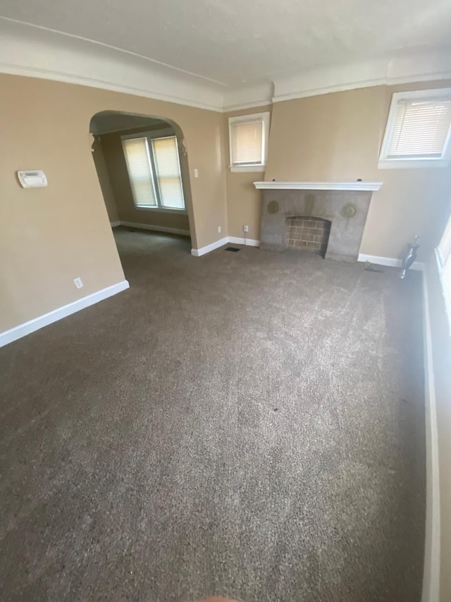 unfurnished living room featuring a fireplace, crown molding, and baseboards