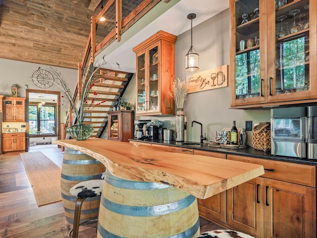 bar featuring dark wood-type flooring, butcher block counters, sink, lofted ceiling with beams, and wooden ceiling