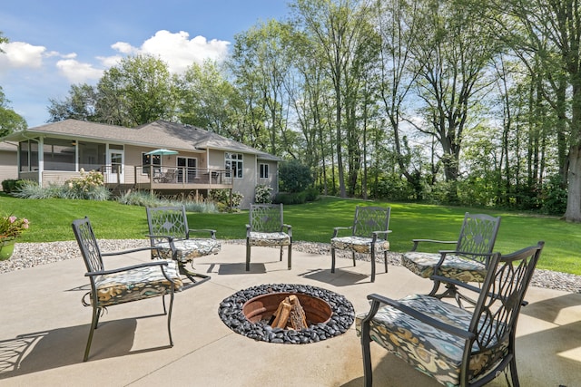 view of patio / terrace with a wooden deck, a sunroom, and an outdoor fire pit