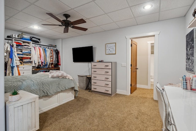 carpeted bedroom with a paneled ceiling and ceiling fan