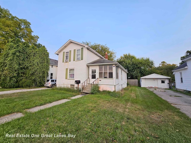 view of front of home with a garage, a front lawn, and an outdoor structure