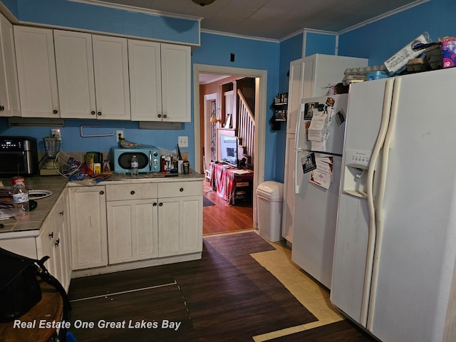 kitchen with white cabinets, dark hardwood / wood-style flooring, white fridge with ice dispenser, and ornamental molding