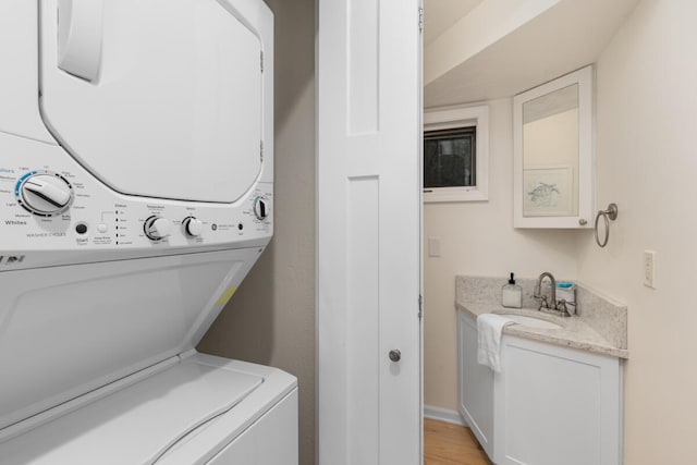 laundry room featuring light wood-type flooring, stacked washer / dryer, and sink