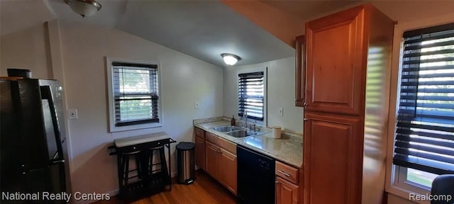 kitchen featuring sink, black appliances, lofted ceiling, and light wood-type flooring