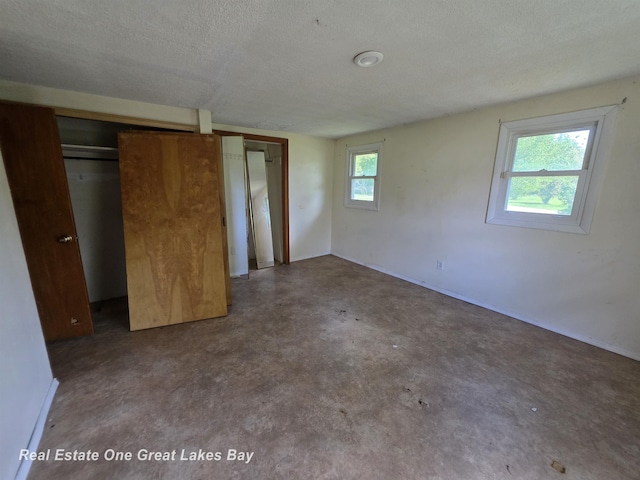 3810 Nicol Dr, Saginaw, MI 48601 - unfurnished bedroom with concrete floors, a textured ceiling, baseboards, and a closet