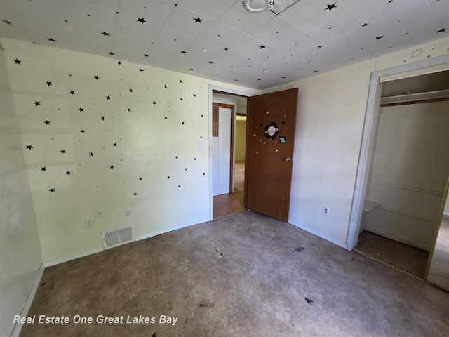 3810 Nicol Dr, Saginaw, MI 48601 - unfurnished bedroom with baseboards, concrete floors, a closet, and a paneled ceiling