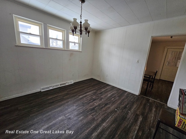 unfurnished room with dark wood-type flooring, crown molding, and a notable chandelier