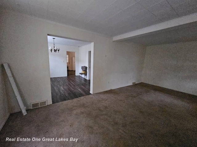 carpeted empty room featuring a notable chandelier