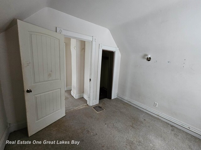 unfurnished bedroom featuring carpet and vaulted ceiling