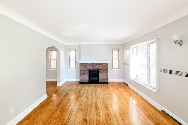 unfurnished living room with a fireplace, a wealth of natural light, and light hardwood / wood-style flooring