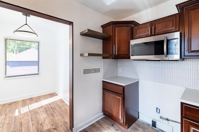 kitchen featuring tasteful backsplash, light hardwood / wood-style flooring, pendant lighting, and dark brown cabinets