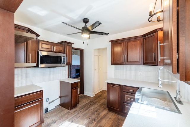 kitchen with ceiling fan with notable chandelier, wood-type flooring, sink, and tasteful backsplash