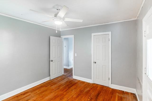 unfurnished bedroom featuring ceiling fan, hardwood / wood-style floors, and crown molding