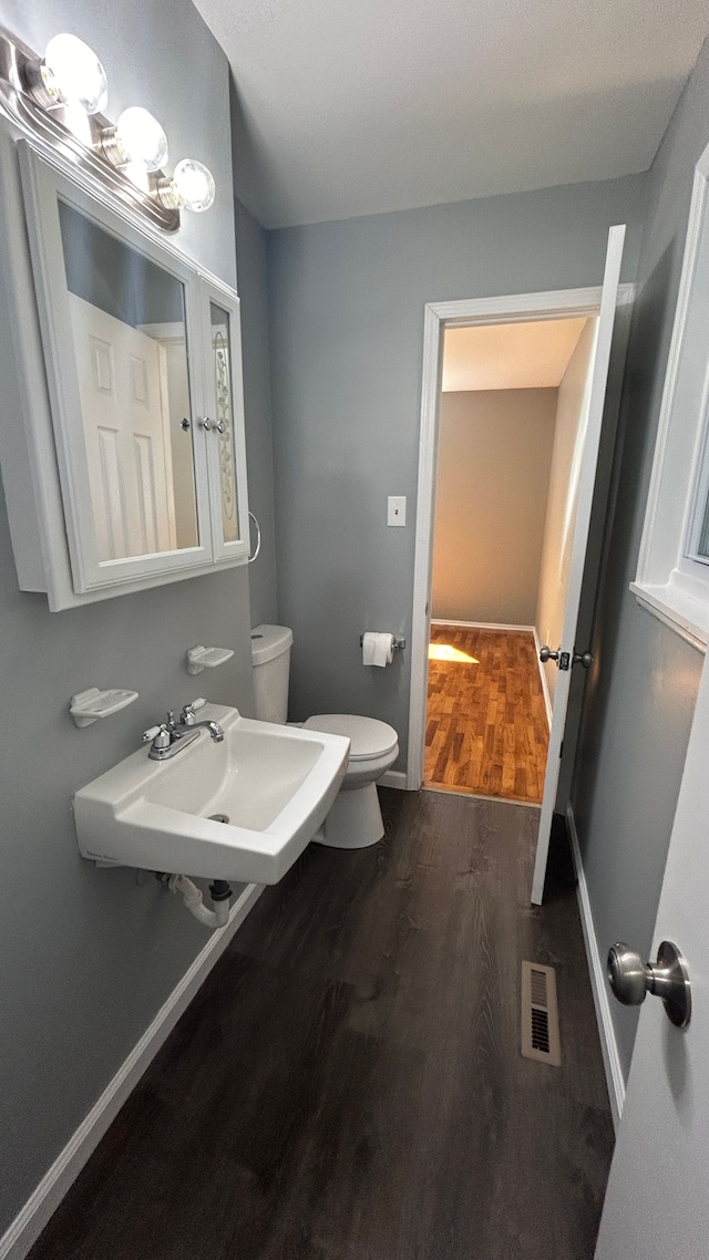 bathroom with toilet, wood-type flooring, and sink