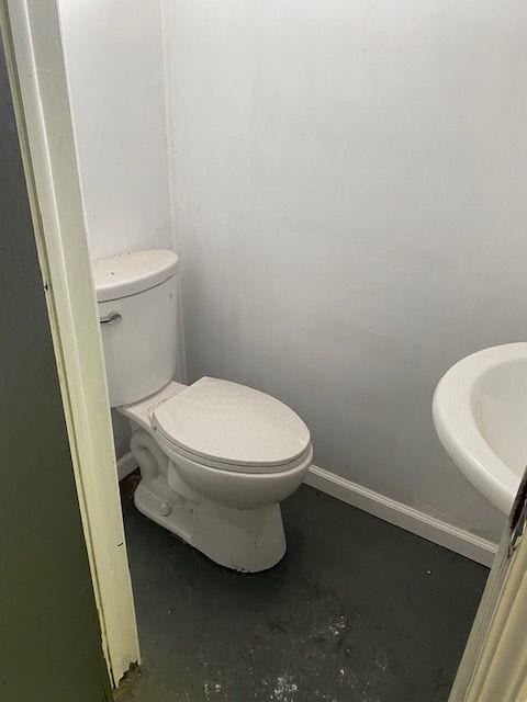 bathroom with toilet, sink, and concrete floors