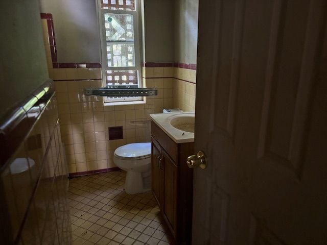 bathroom featuring toilet, vanity, tile patterned floors, and tile walls