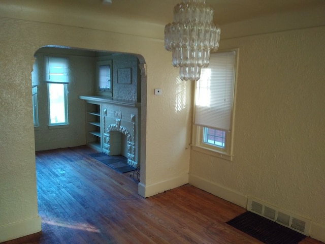 unfurnished dining area with a wealth of natural light, hardwood / wood-style floors, and an inviting chandelier