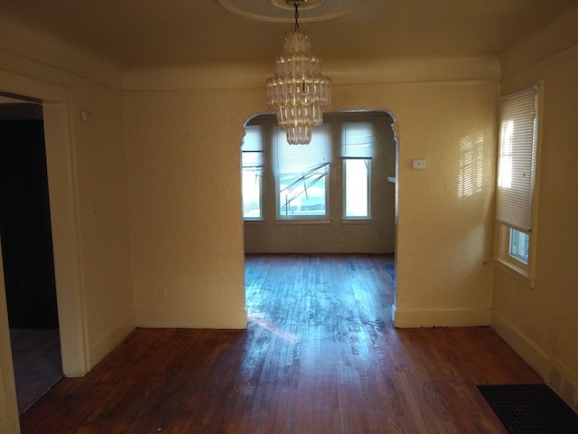 unfurnished dining area featuring a chandelier and dark hardwood / wood-style floors