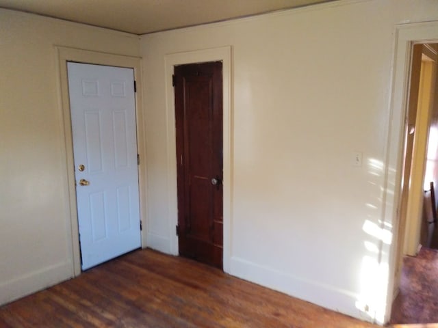 unfurnished bedroom featuring a closet and dark wood-type flooring