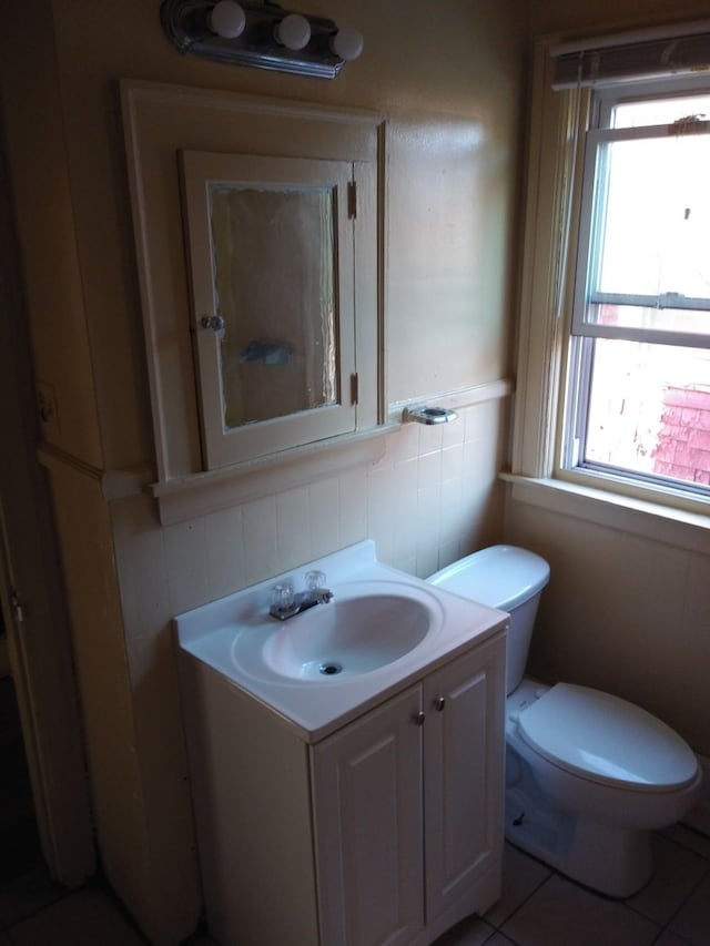 bathroom featuring toilet, plenty of natural light, vanity, and tile patterned flooring