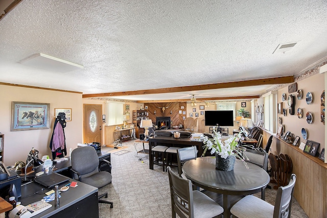 carpeted dining area with a textured ceiling, ceiling fan, crown molding, and wood walls