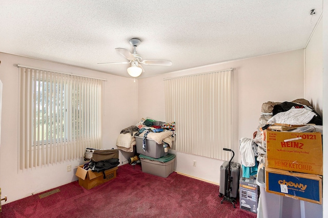 misc room featuring a textured ceiling, dark carpet, and ceiling fan