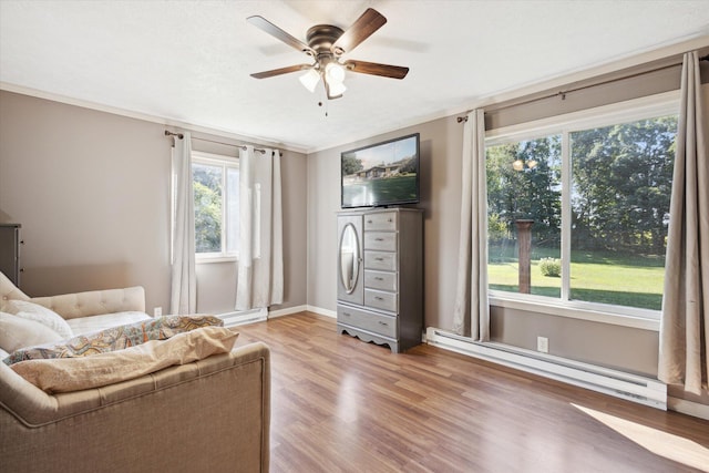 sitting room with ceiling fan, ornamental molding, a baseboard heating unit, and light wood-type flooring