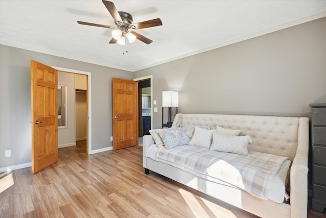 bedroom featuring a walk in closet, light hardwood / wood-style floors, and ceiling fan