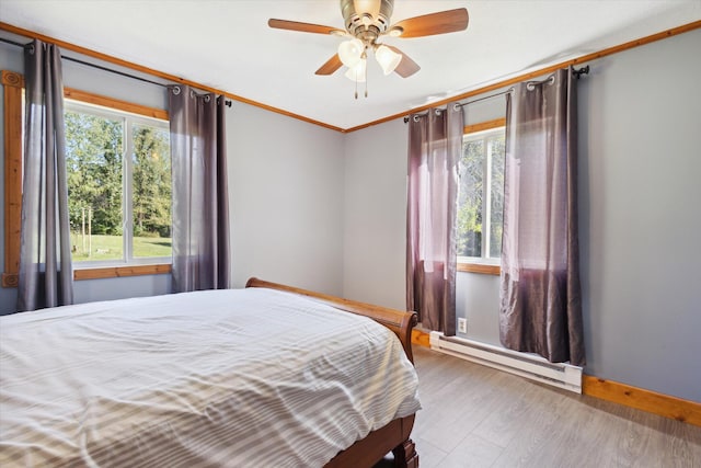 bedroom with hardwood / wood-style flooring, crown molding, ceiling fan, and a baseboard heating unit