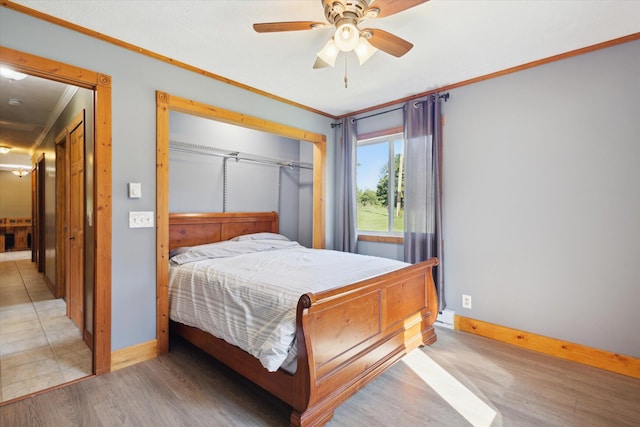 bedroom featuring hardwood / wood-style flooring, ceiling fan, crown molding, and a closet