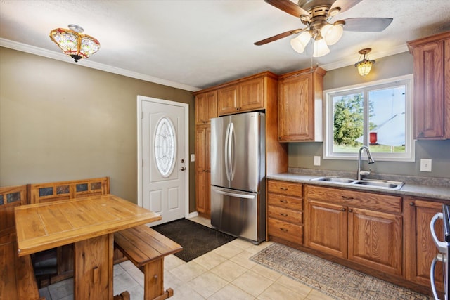 kitchen with crown molding, sink, ceiling fan, light tile patterned floors, and stainless steel refrigerator