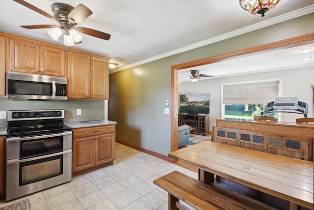 kitchen with appliances with stainless steel finishes, ceiling fan, ornamental molding, and light tile patterned flooring