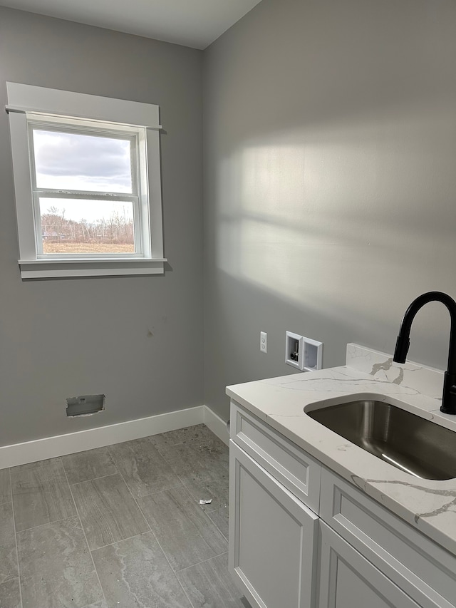 clothes washing area featuring cabinets, sink, and washer hookup