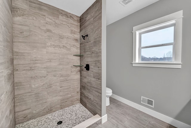 bathroom with tiled shower and toilet