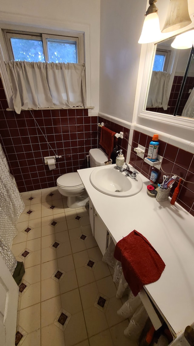 bathroom with tile patterned flooring, vanity, toilet, and tile walls