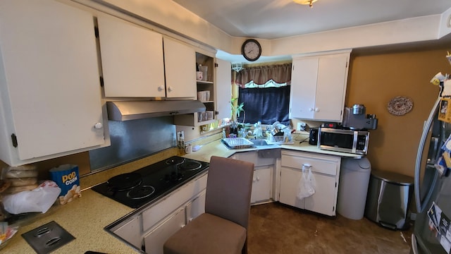 kitchen with black electric stovetop, refrigerator, white cabinetry, and range hood