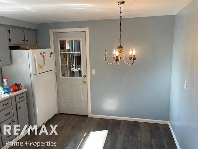 kitchen with gray cabinetry, white refrigerator, dark hardwood / wood-style floors, decorative light fixtures, and a chandelier