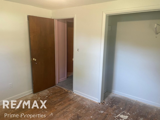 unfurnished bedroom featuring a closet and dark wood-type flooring