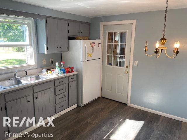 kitchen featuring dark hardwood / wood-style flooring, white refrigerator, hanging light fixtures, and sink