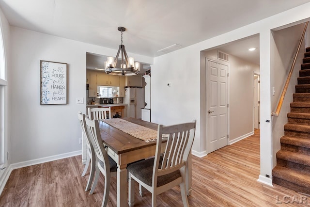 dining room with light hardwood / wood-style floors and an inviting chandelier