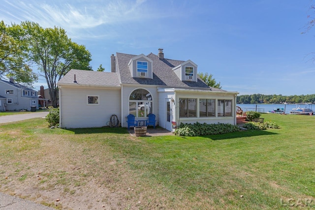 rear view of house featuring a sunroom, a yard, and a water view