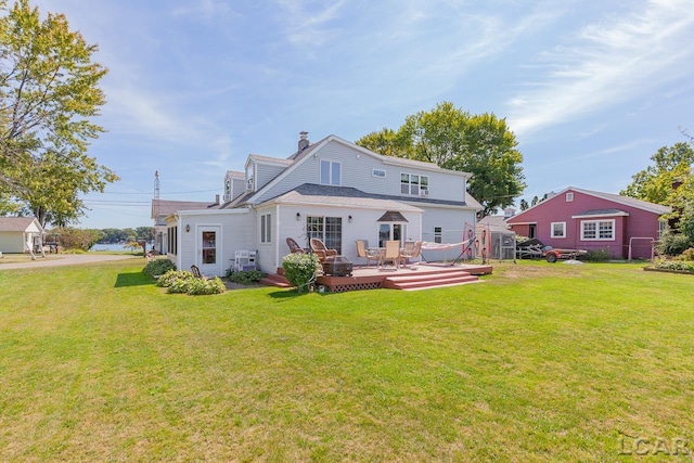 rear view of property featuring a shed, a deck, and a yard