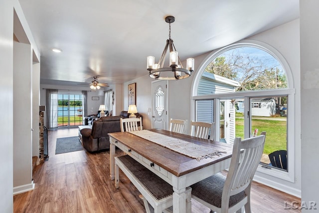 dining area with ceiling fan with notable chandelier and hardwood / wood-style flooring