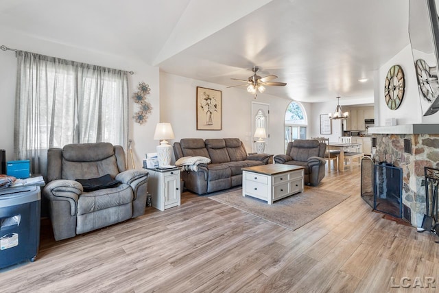 living room with a fireplace, ceiling fan with notable chandelier, and light hardwood / wood-style flooring