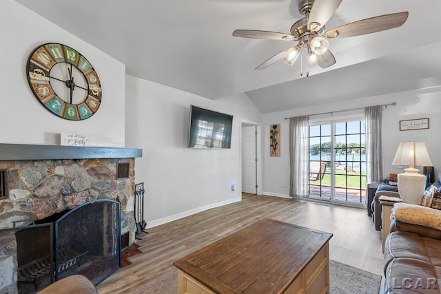 living room featuring a fireplace, ceiling fan, light hardwood / wood-style flooring, and lofted ceiling