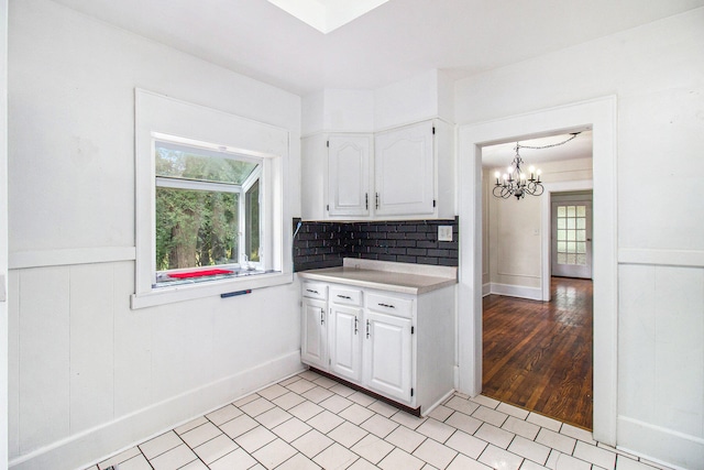 kitchen with a notable chandelier, white cabinetry, backsplash, and light hardwood / wood-style flooring