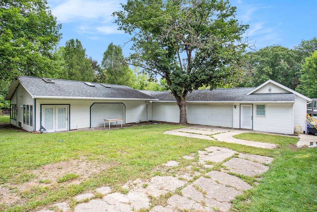 rear view of property with a garage and a lawn