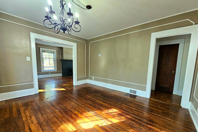 unfurnished dining area with a fireplace, a chandelier, crown molding, and dark wood-type flooring